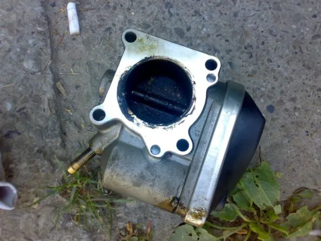 Interior clapetă de accelerație acoperit cu depuneri groase de carbon și ulei înainte de curățare